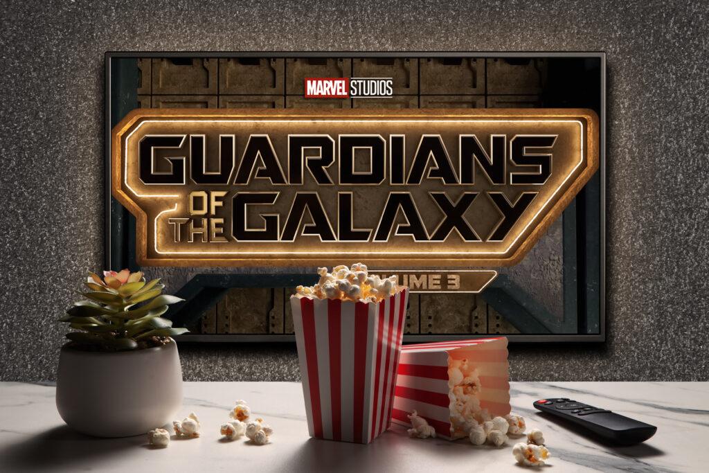 TV screen playing Guardians Of The Galaxy Volume 3 trailer or movie. TV with remote control, popcorn boxes and home plant. Moscow, Russia - January 6, 2023.